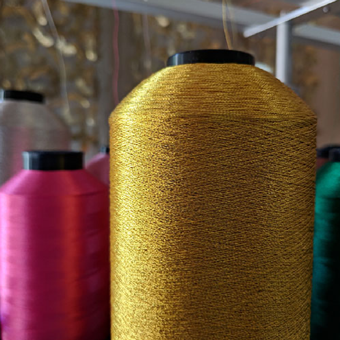 Side view of thread spools. Colors: gold, pink, white.