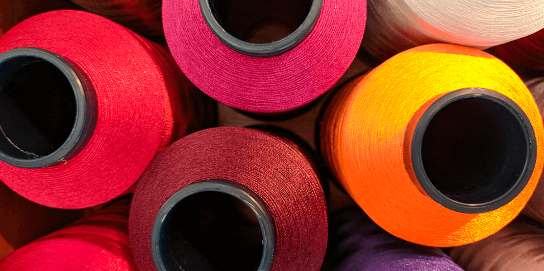 Top view of thread spools. Colors: red, pink, burgandy, yellow, white.